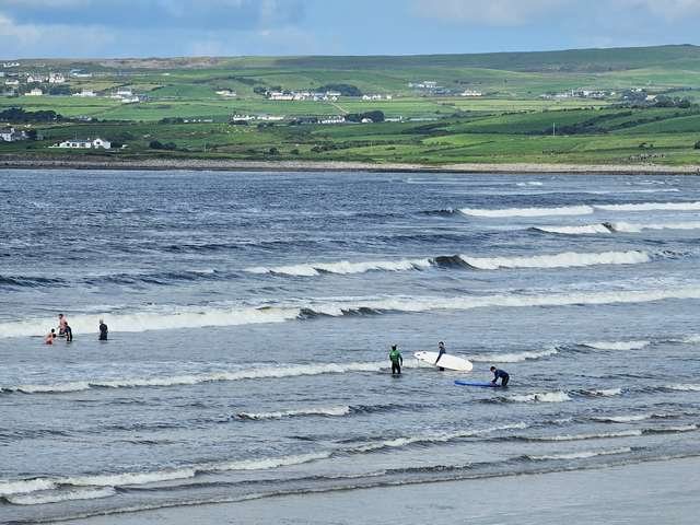 aaa few beginner surfers in the shallows making their way deeper to catch some waves